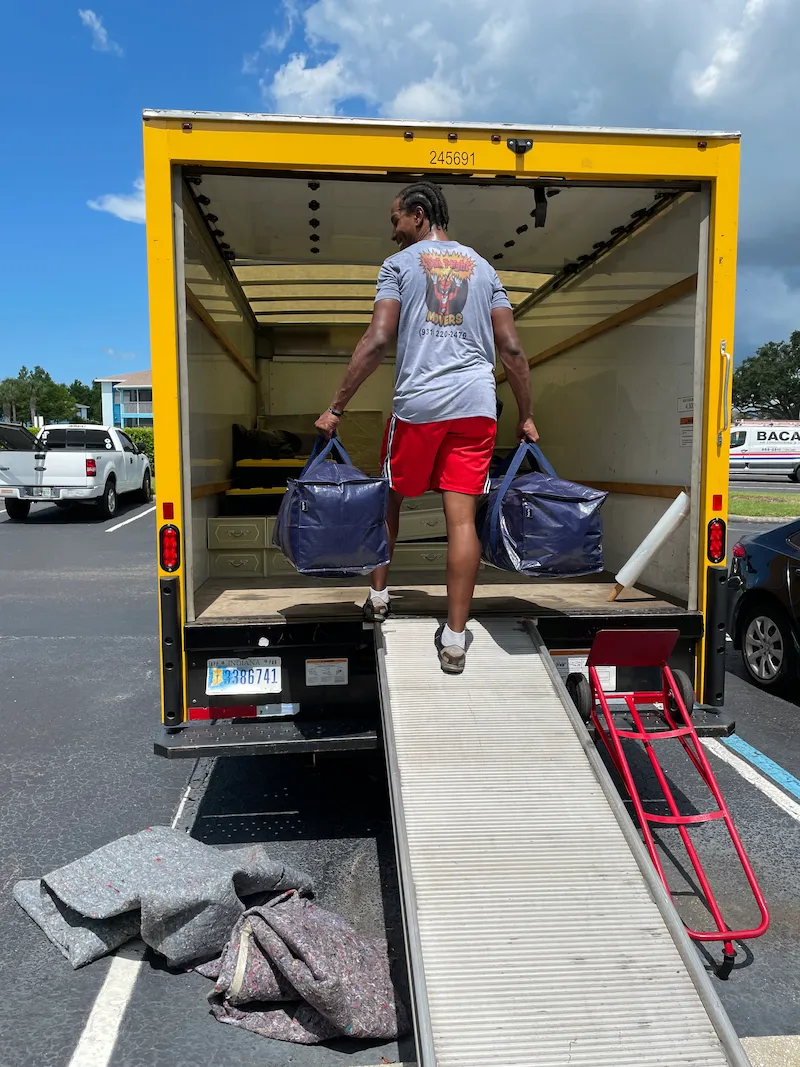 A DynaMight Movers crew member loading bags into the back of the moving truck.